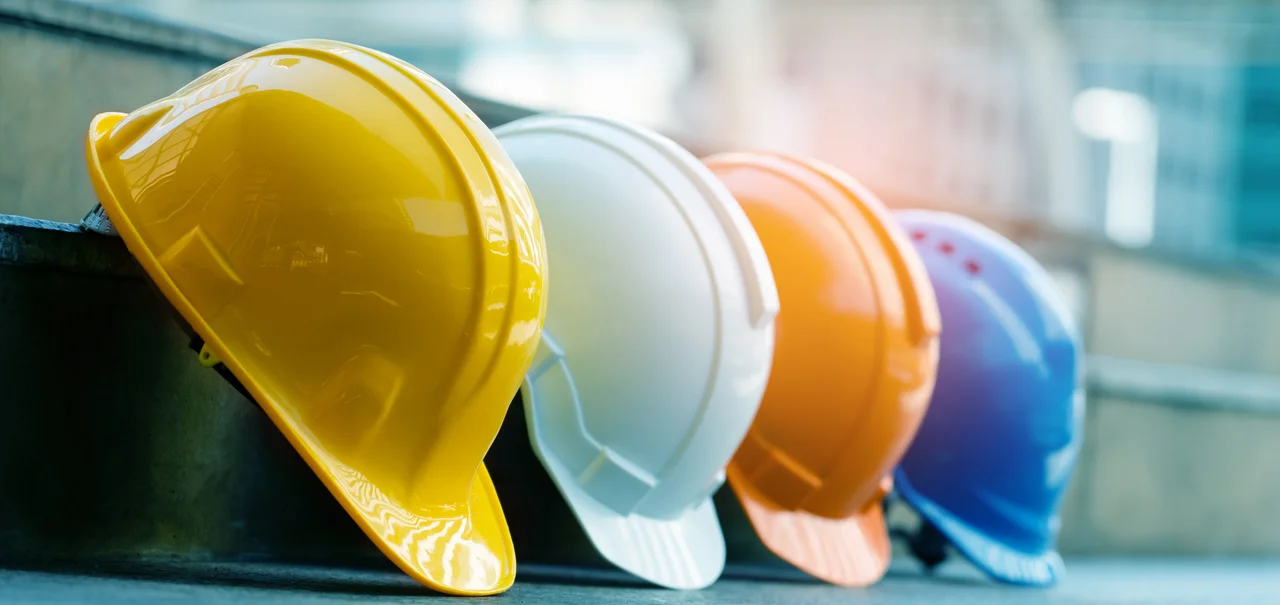Sicherheit am Arbeitsplatz. Aufgereihte Bauhelme in unterschiedlichen Farben - Sicherheit am Arbeitsplatz. Aufgereihte Bauhelme in unterschiedlichen Farben