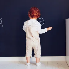 Beschriften - niedliche Rothaarige Babyjungen Zeichnung an der Kreide-Wand zu Hause - Stock-Fotografie